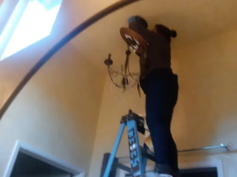 Electrician installing a chandelier in a Baraga residence